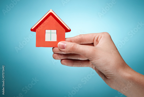 woman s hand holding sign of the house. Against blue background