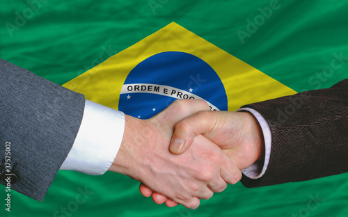 businessmen handshake after good deal in front of brazil flag
