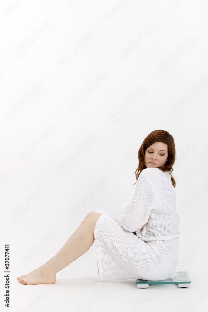 young beuatiful woman sitting on a bathroom scale young beuatiful woman sitting on a bathroom scale