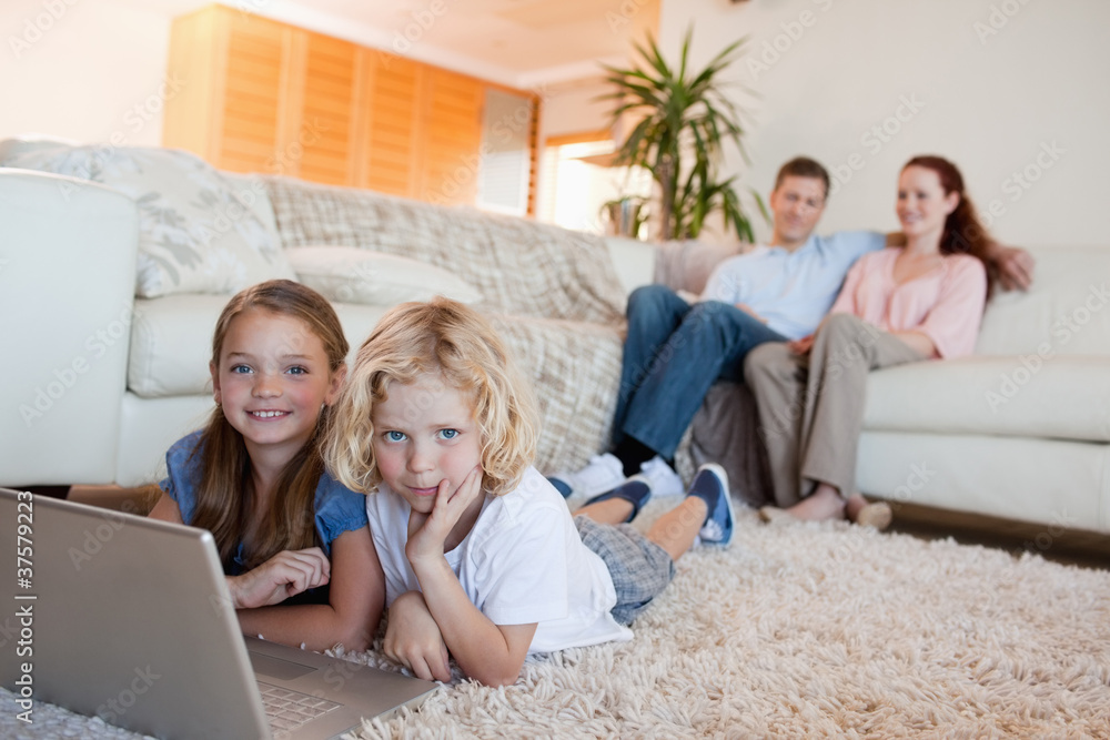 Siblings with notebook on the floor Siblings with notebook on the floor