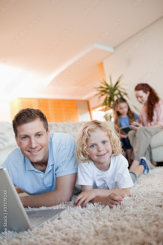 Father and son using internet on the floor Father and son using internet on the floor