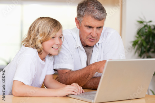 Father and son using laptop in the kitchen