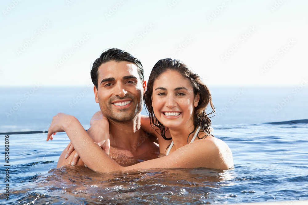 Obraz premium Smiling couple embracing in the pool
