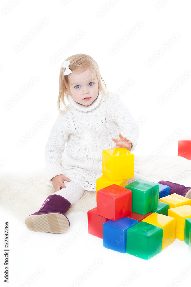 Baby girl plays with toy blocks over white background Baby girl plays with toy blocks over white background