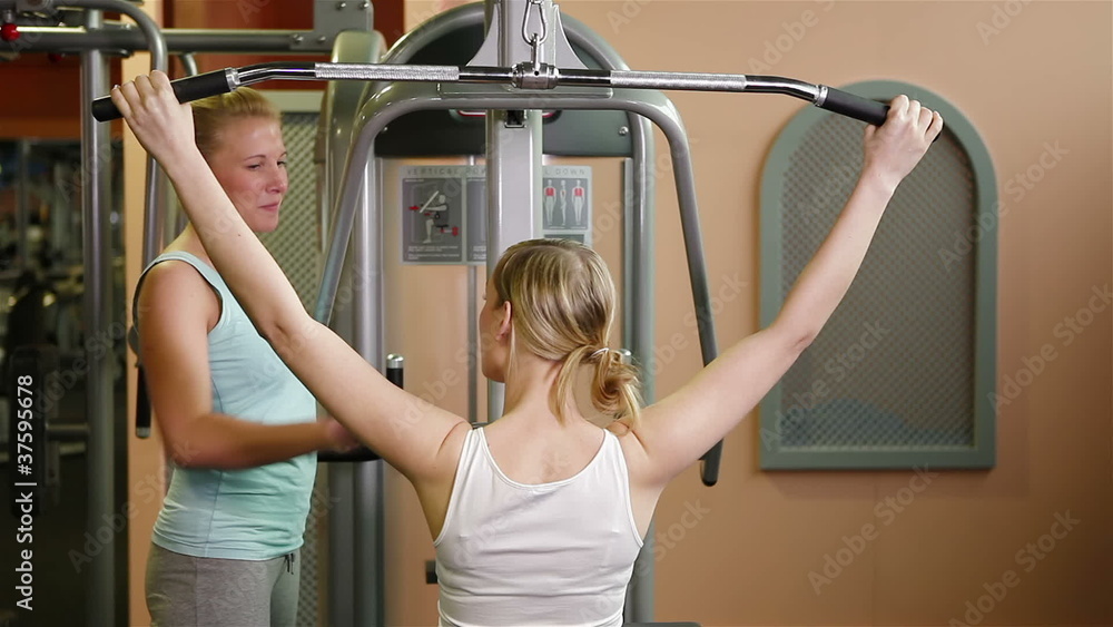 Fitness trainer explaining lat machine in gym Stock Video | Adobe Stock