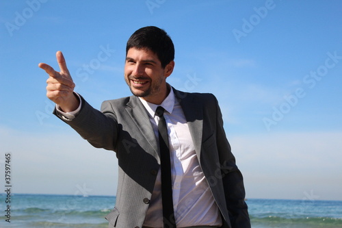 Fototapeta A young businessman pointing his hand like a gun