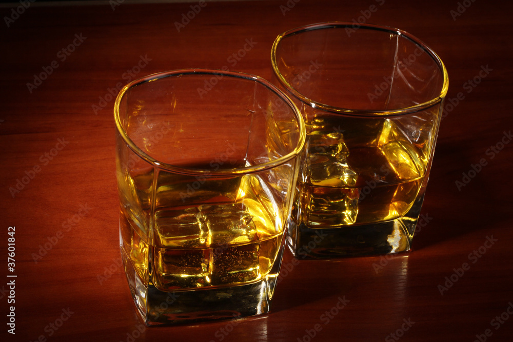 two glasses of scotch whiskey and ice on wooden table two glasses of scotch whiskey and ice on wooden table