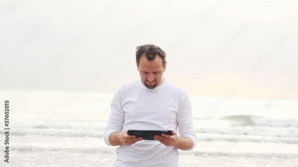 Happy young man with tablet computer on the beach Happy young man with tablet computer on the beach