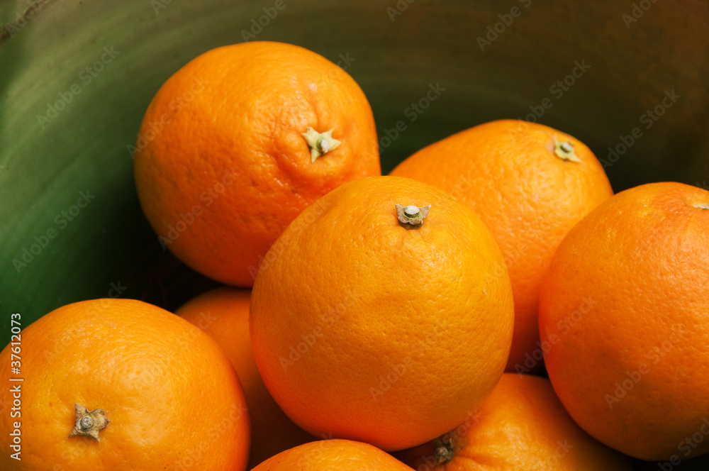 Some oranges fruits in a green bowl Some oranges fruits in a green bowl