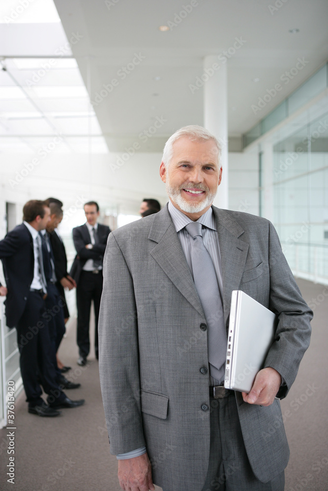 Fototapeta premium Senior businessman standing in a corridor