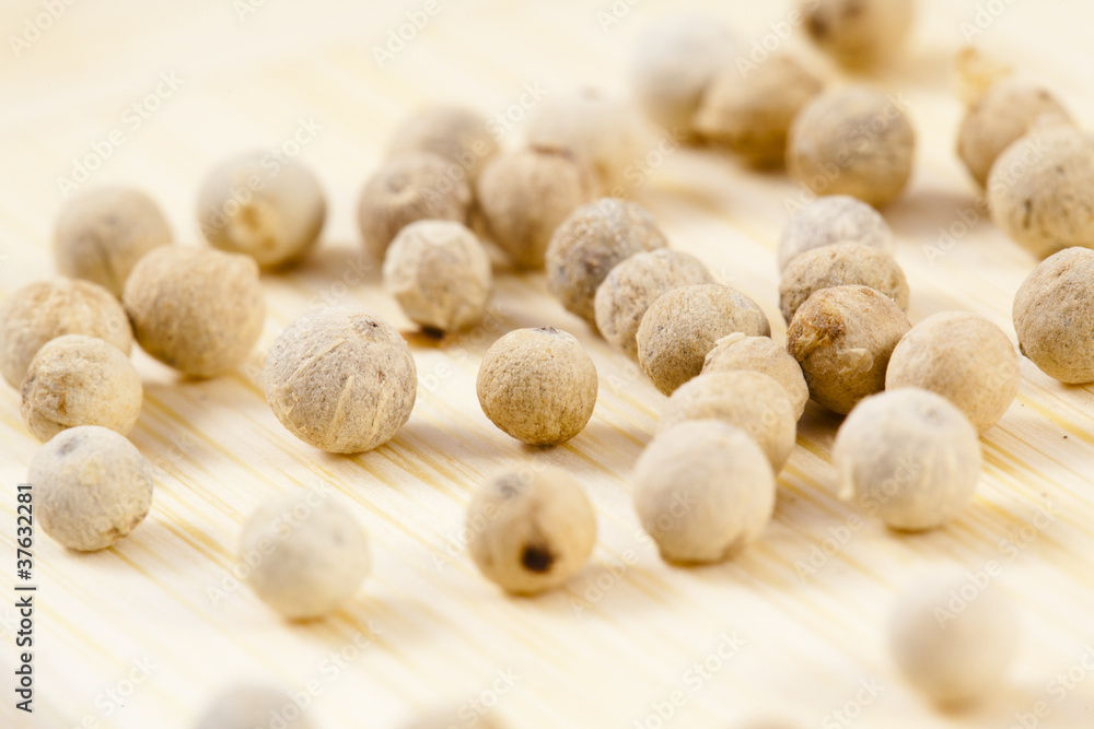 white pepper corns close up on a wooden board