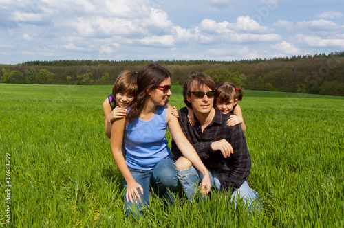 Happy family with kids outdoors on green field,