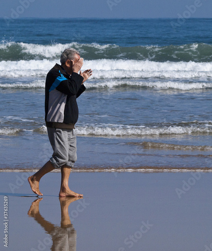 Anciano paseando por la orilla del mar
