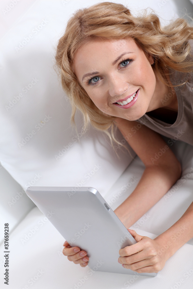 Smiling blond woman at home using electronic tablet Smiling blond woman at home using electronic tablet