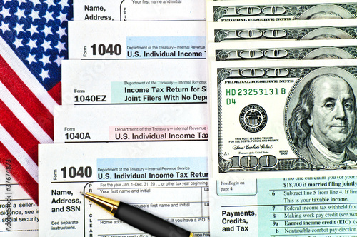 Tax forms with pen, money and U.S. flag.