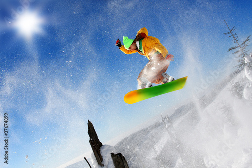 Snowboarder jumping against blue sky