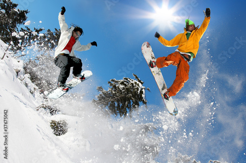Snowboarders jumping against blue sky #37675042
