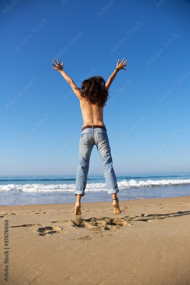 back of woman jumping at seashore