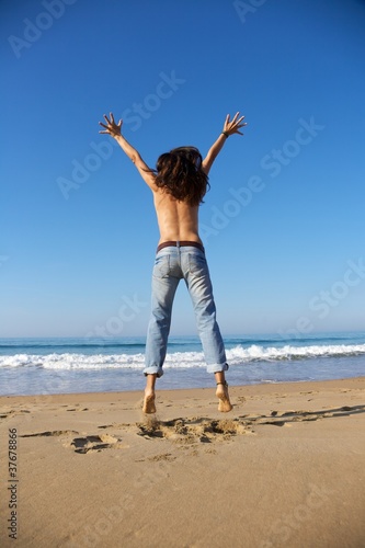 back of woman jumping at seashore