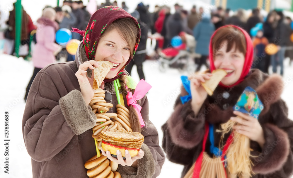 Smiling girls eating pancake during  Shrovetide