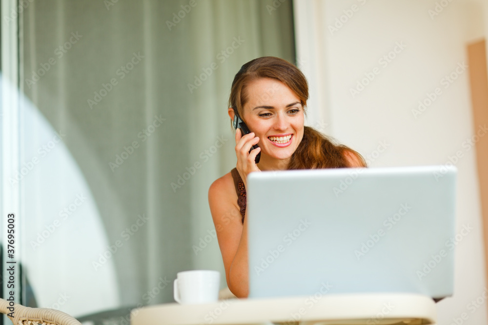 Smiling young woman on terrace speaking cell phone