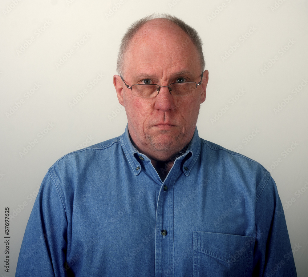 Older Man in Blue Denim Shirt and Glasses Looking Glum Older Man in Blue Denim Shirt and Glasses Looking Glum