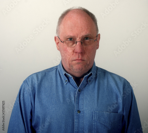 Older Man in Blue Denim Shirt and Glasses Looking Glum