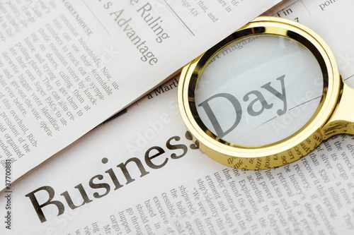 Loupe lies on the newspaper with title Business day