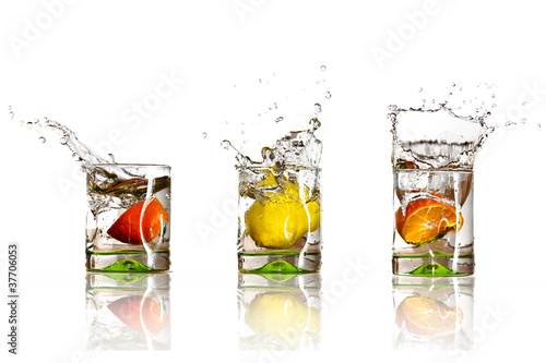 Drinks with splashing citrus fruits over white