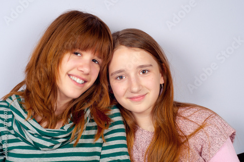 Portrait of two pretty teenage girlfriends smiling
