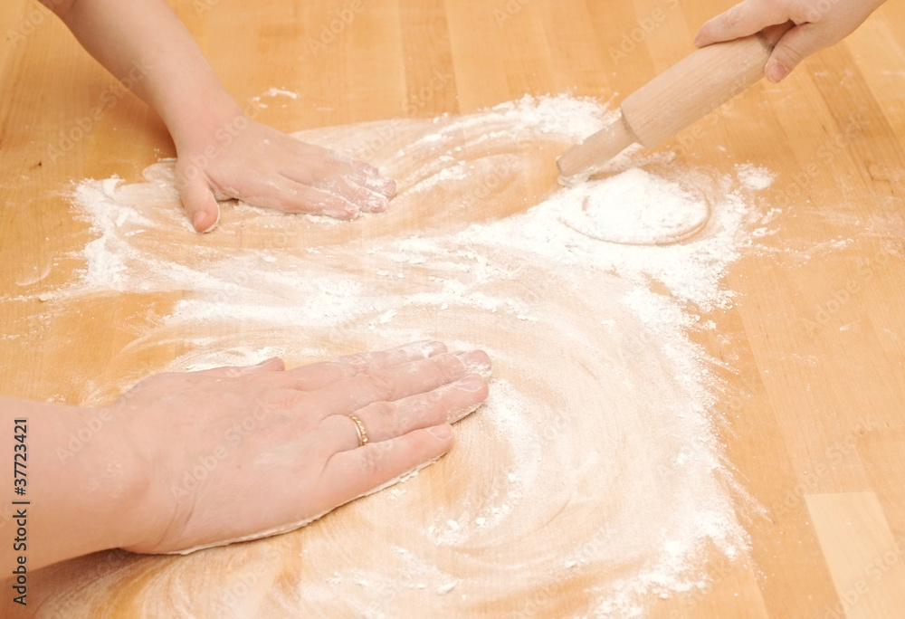Fototapeta premium A child is helping mom to knead the dough for baking