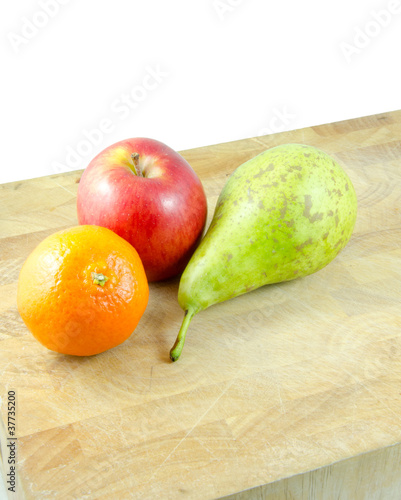 orange, pear and apple on chopping board