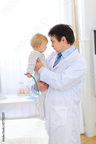 Portrait of pediatric doctor playing with baby