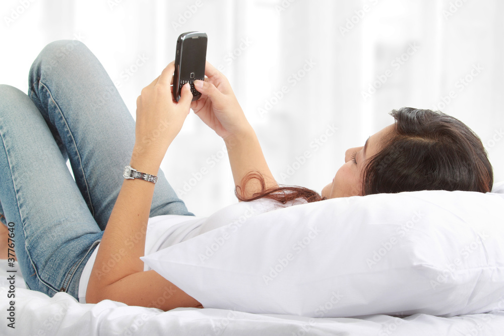 woman texting on phone lying on the bed woman texting on phone lying on the bed