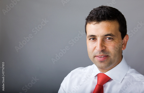 Portrait of smiling young business man on grey background