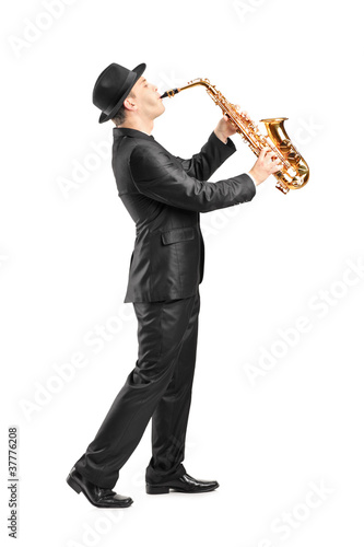 Full length portrait of a man in a suit playing on saxophone