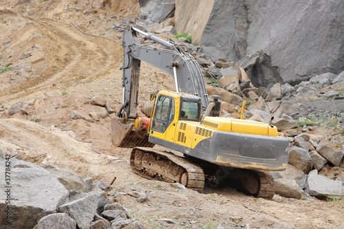 Closeup of an excavator moving on top level of a granite mine