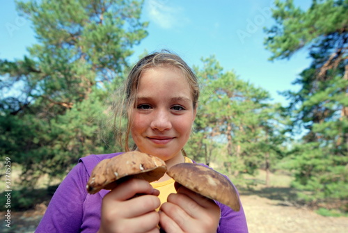 A teenage girl is holding a boletus mushrooms. Search and collection of edible mushrooms in the forest. Outdoor hobby. Seasonal mushroom picking
