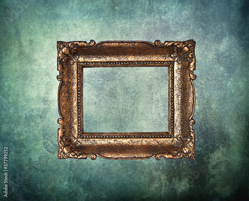 Empty golden frame on grunge old wall