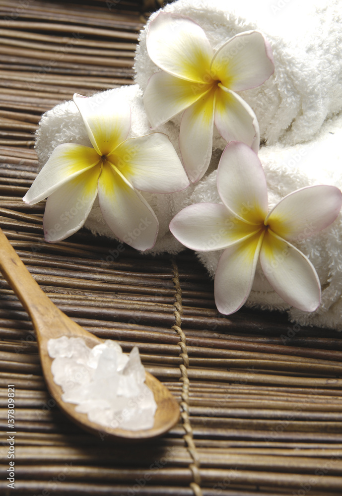 frangipani and roller towel with salt in spoon on mat frangipani and roller towel with salt in spoon on mat