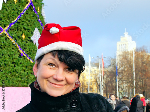 Obraz na plátně happy woman in cap Santa Claus near  New Year's fur-tree