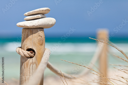 Stones balanced on wooden banister near the beach. #37824005