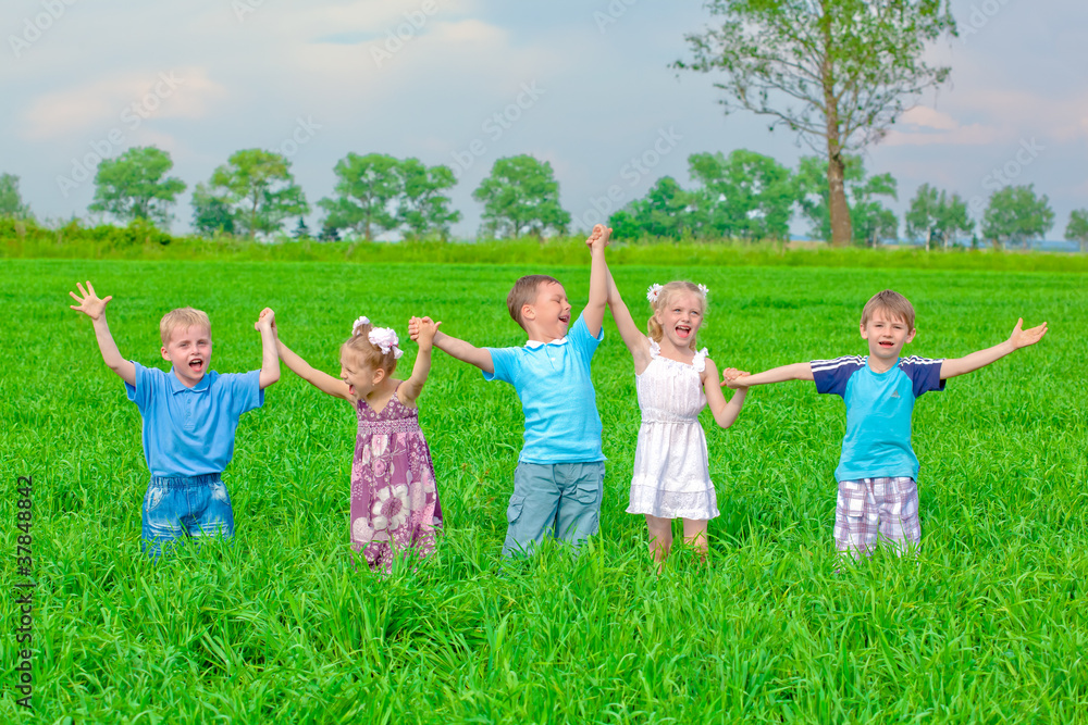 Funny kids standing on grass holding hands up