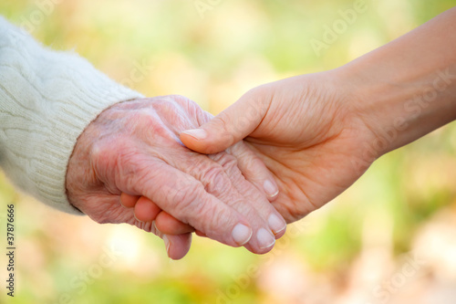 Senior and young holding hands