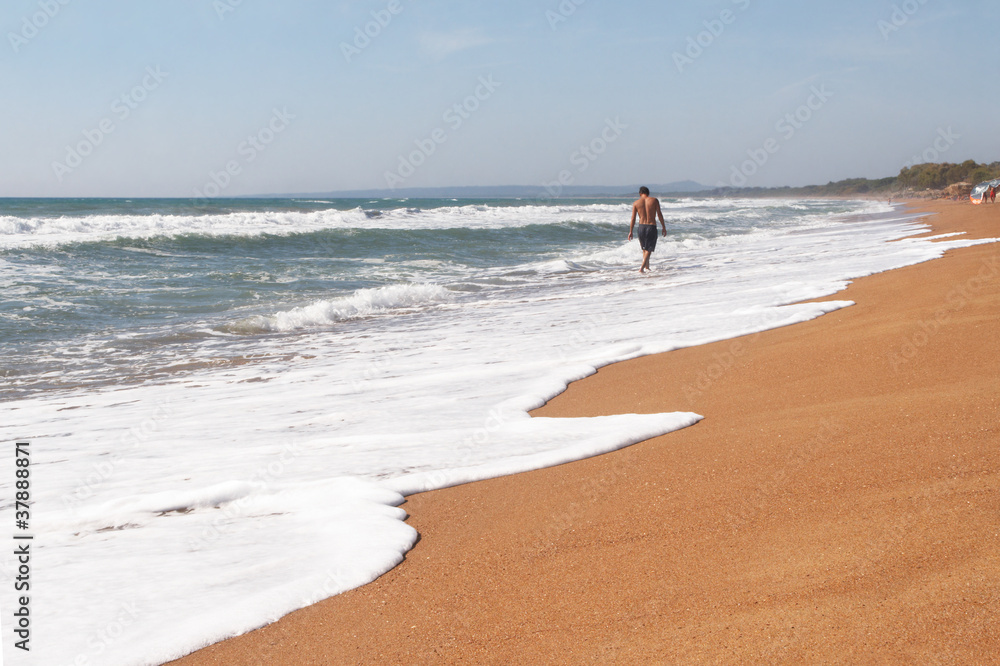 Fotografie A young man walks on deserted beach