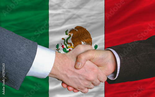 businessmen handshake after good deal in front of mexico flag