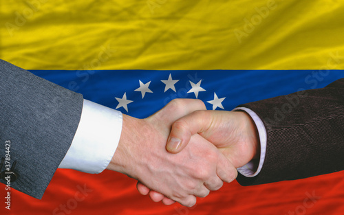 businessmen handshake after good deal in front of venezuela flag