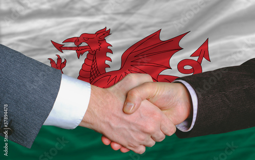 businessmen handshake after good deal in front of wales flag photo