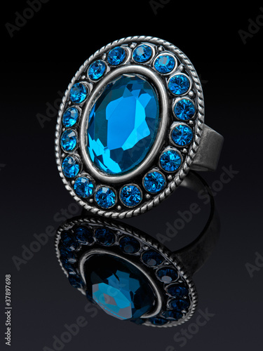 Silver ring with blue stones (glass) with reflection.