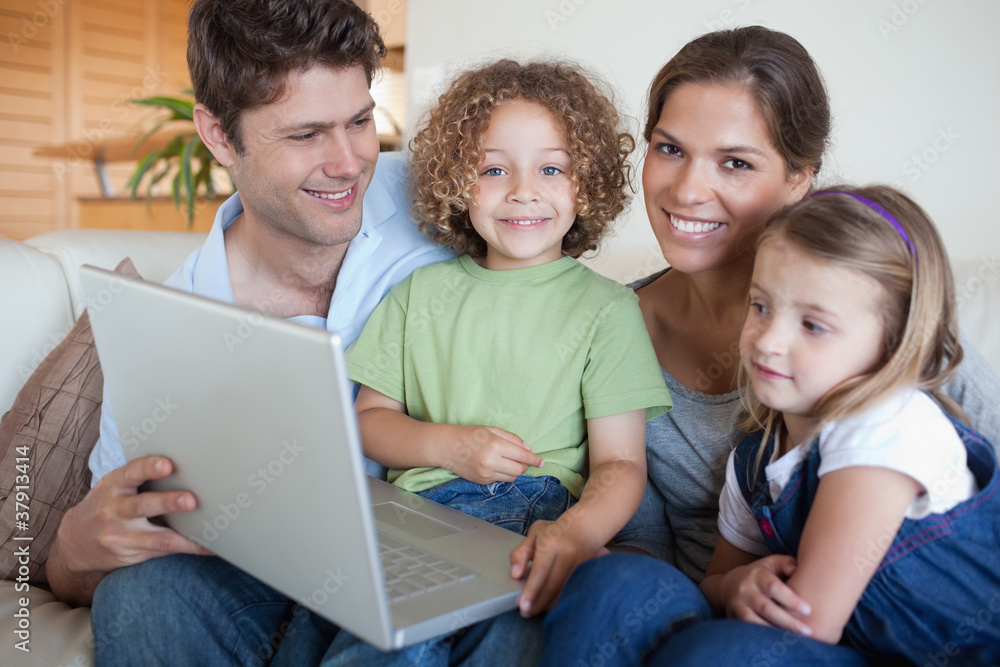 Smiling family using a laptop